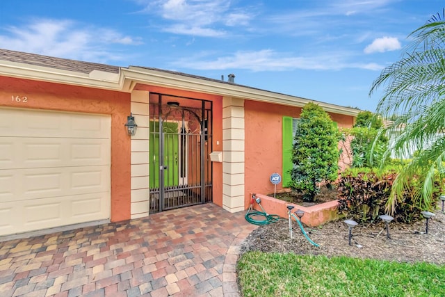 view of exterior entry with a garage and stucco siding