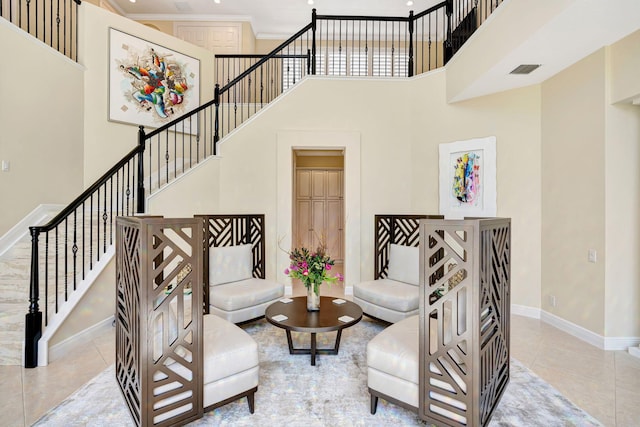 interior space with a high ceiling, tile patterned flooring, visible vents, and baseboards