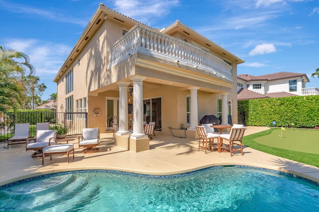 back of house with a fenced in pool, a patio, stucco siding, fence, and a balcony