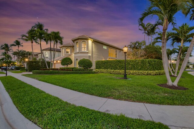 mediterranean / spanish-style home with an attached garage, a tiled roof, decorative driveway, and stucco siding