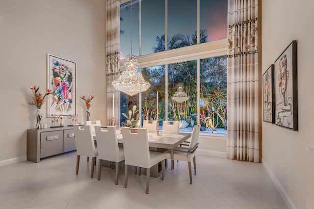 dining space with a chandelier, a towering ceiling, and baseboards