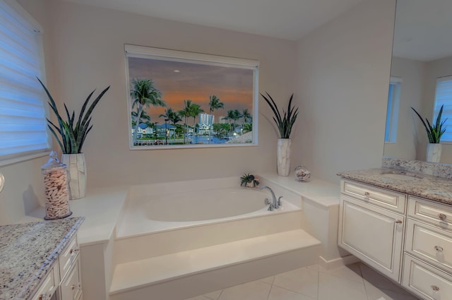 bathroom with a garden tub, vanity, and tile patterned floors