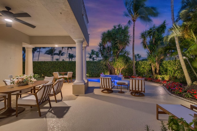 patio terrace at dusk featuring a ceiling fan, outdoor dining space, and a fenced in pool