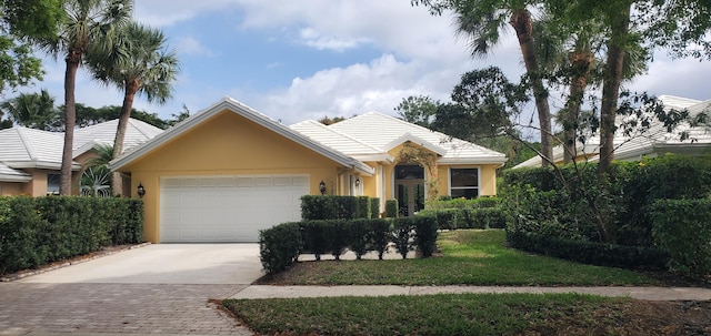 ranch-style house with driveway, an attached garage, and stucco siding