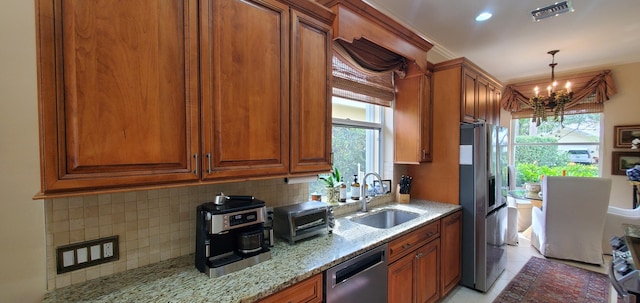 kitchen with light stone counters, stainless steel appliances, visible vents, backsplash, and a sink