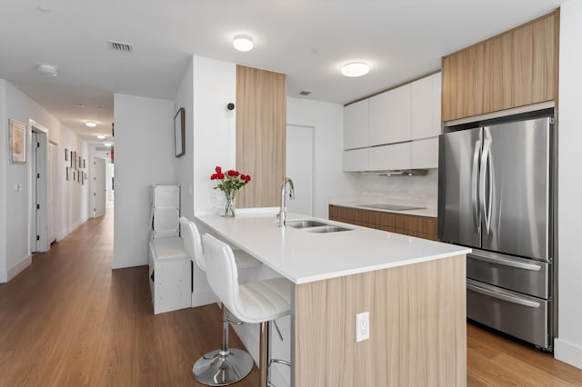 kitchen featuring light countertops, freestanding refrigerator, white cabinetry, a sink, and a peninsula