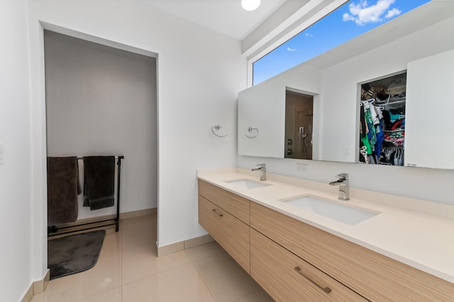 bathroom featuring double vanity, tile patterned flooring, a walk in closet, and a sink