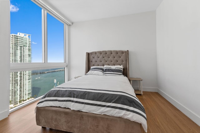 bedroom with baseboards, a wall of windows, and wood finished floors