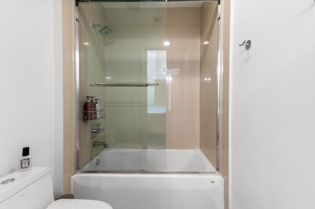 bathroom with combined bath / shower with glass door and toilet