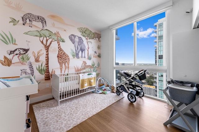 bedroom featuring a wall of windows and wood finished floors