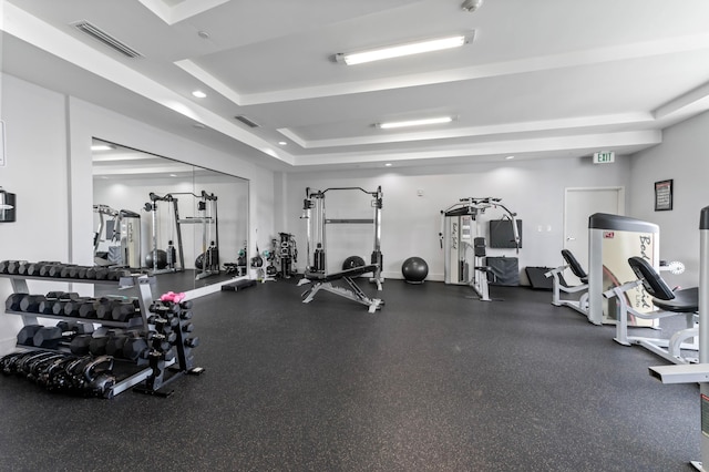 workout area with a tray ceiling, visible vents, baseboards, and recessed lighting