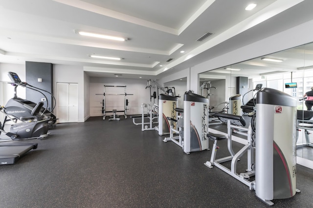 workout area featuring recessed lighting, a raised ceiling, and visible vents