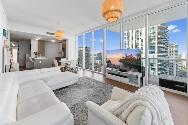 living area featuring a wall of windows, visible vents, and wood finished floors