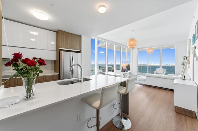 kitchen featuring a water view, white cabinetry, light countertops, freestanding refrigerator, and modern cabinets