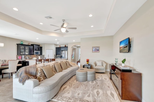 living room featuring arched walkways, recessed lighting, a ceiling fan, visible vents, and a raised ceiling