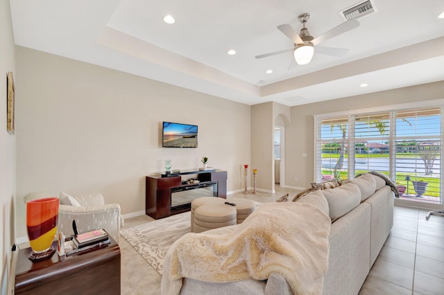 living area with baseboards, visible vents, a raised ceiling, arched walkways, and recessed lighting