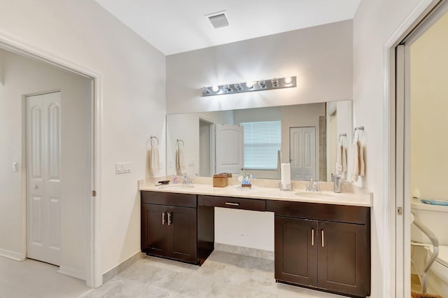 bathroom with toilet, double vanity, a sink, and visible vents