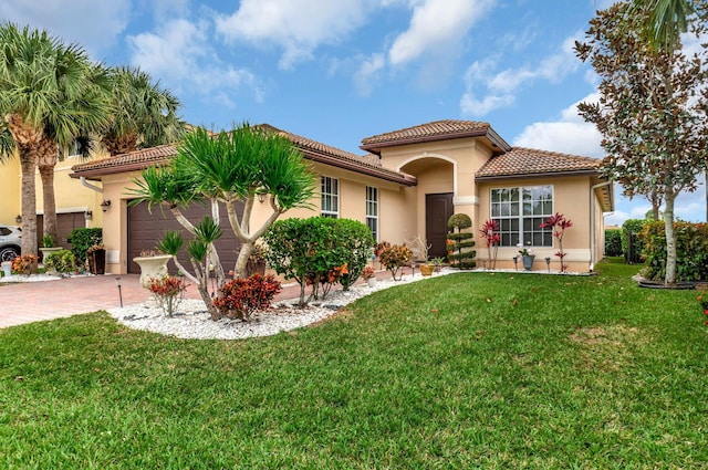 mediterranean / spanish-style home featuring decorative driveway, a tile roof, stucco siding, a front yard, and a garage