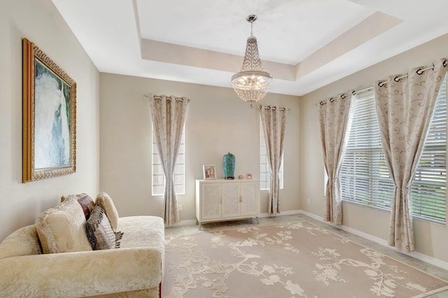 sitting room with a notable chandelier, a raised ceiling, and baseboards