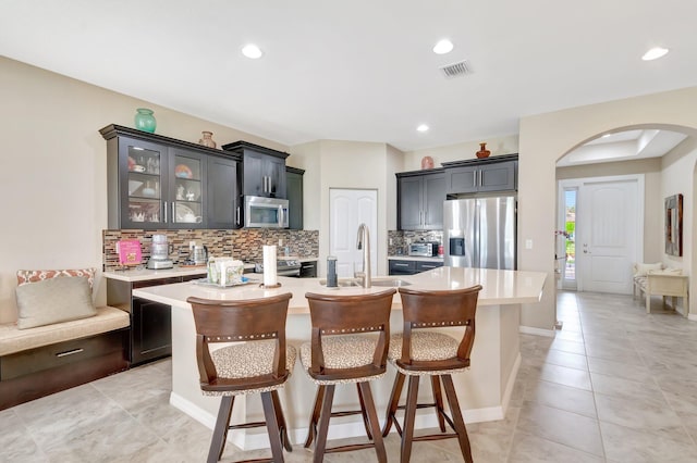 kitchen with visible vents, decorative backsplash, arched walkways, appliances with stainless steel finishes, and light countertops