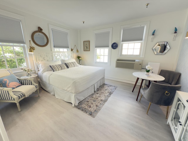 bedroom featuring multiple windows, a wall unit AC, and light wood finished floors