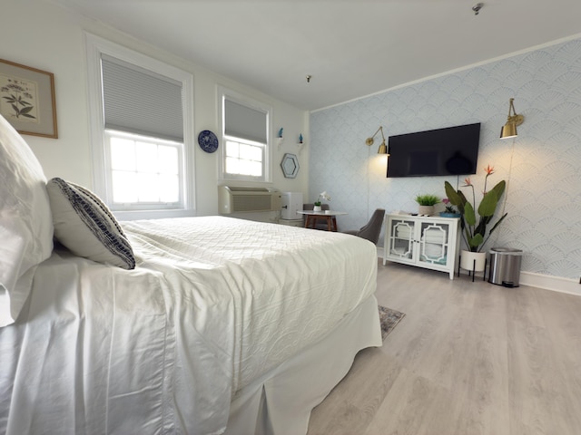 bedroom with wallpapered walls, baseboards, a wall unit AC, ornamental molding, and wood finished floors