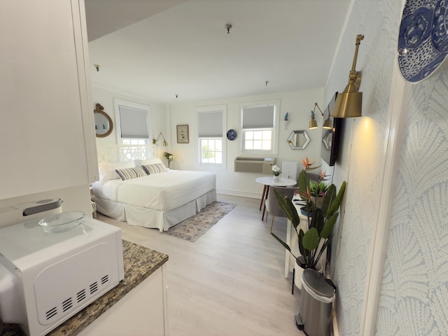 bedroom with light wood-style flooring and a wall mounted AC