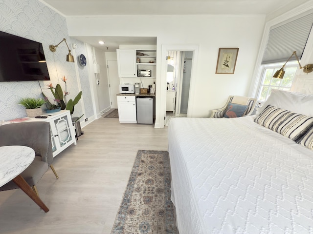 bedroom with wallpapered walls, baseboards, light wood-style floors, an accent wall, and fridge