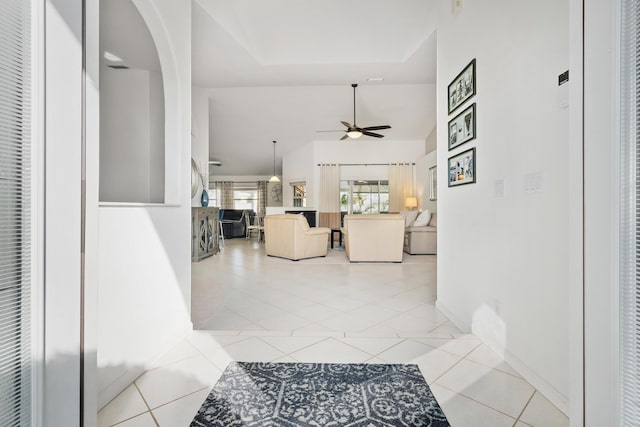 corridor featuring baseboards, arched walkways, and light tile patterned flooring