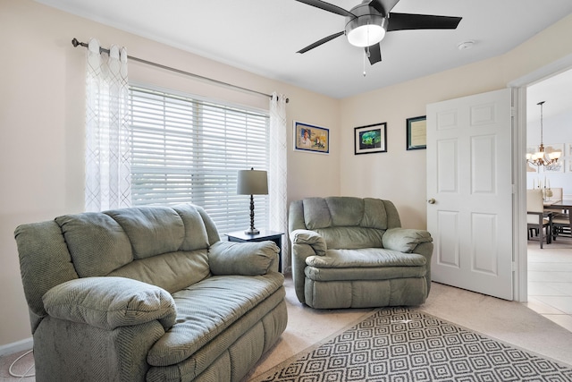 living area with ceiling fan with notable chandelier and light colored carpet