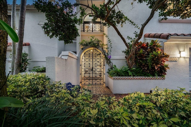 exterior space with a tiled roof, a gate, and stucco siding