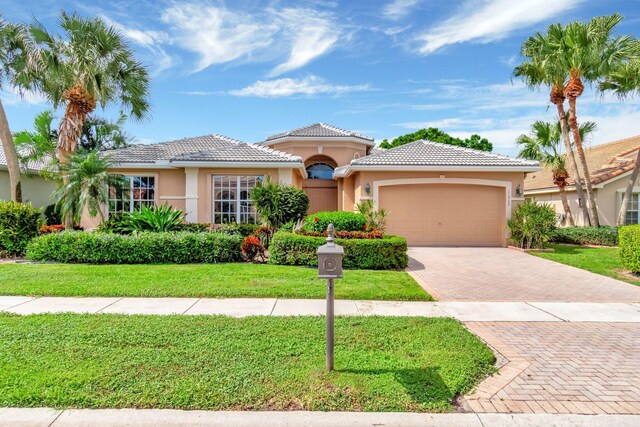 mediterranean / spanish-style house with a front yard, decorative driveway, an attached garage, and stucco siding