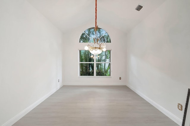 empty room with a chandelier, lofted ceiling, visible vents, and baseboards