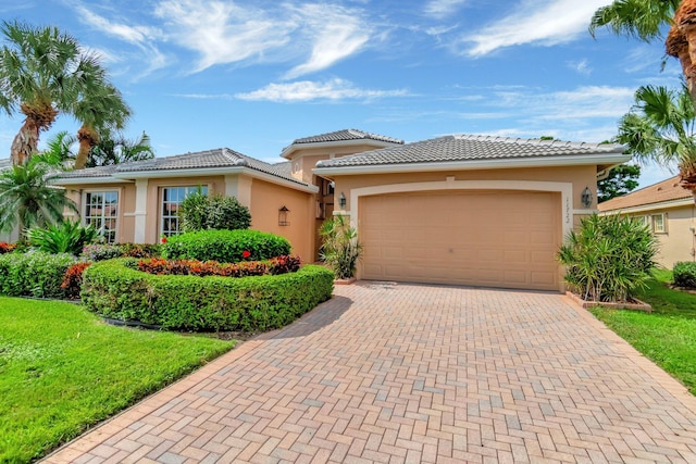 view of front facade featuring an attached garage, a tiled roof, decorative driveway, and stucco siding