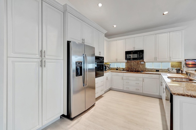 kitchen with black appliances, light stone counters, white cabinets, and a sink