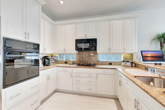 kitchen with recessed lighting, backsplash, white cabinetry, light stone countertops, and black appliances