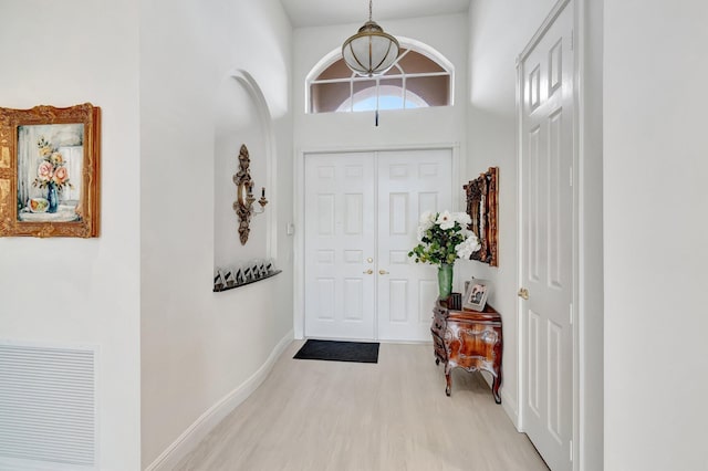 foyer entrance with light wood-type flooring, baseboards, and visible vents