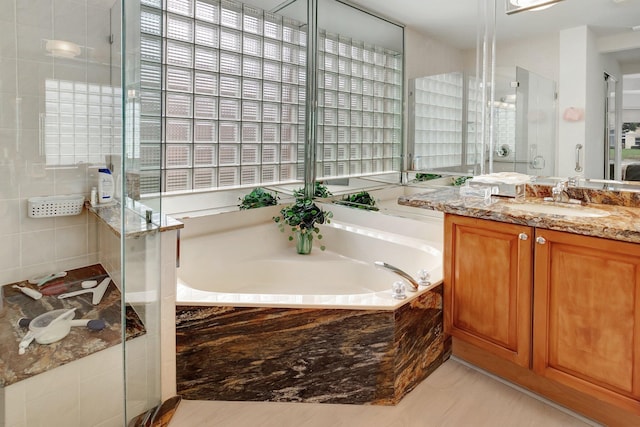 bathroom with a stall shower, a bath, and vanity