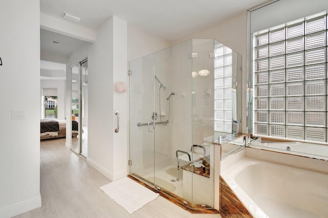 ensuite bathroom with visible vents, connected bathroom, wood finished floors, a garden tub, and a shower stall