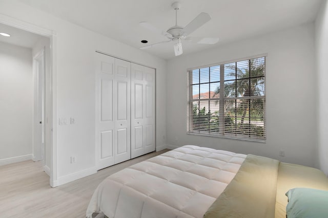bedroom featuring a closet, baseboards, ceiling fan, and light wood finished floors