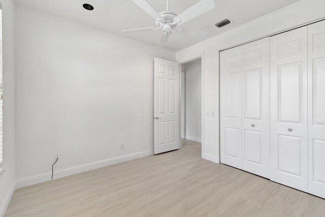 unfurnished bedroom featuring light wood-type flooring, a closet, visible vents, and baseboards