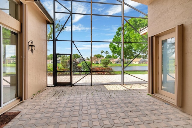interior space featuring a sunroom, a water view, and a textured wall