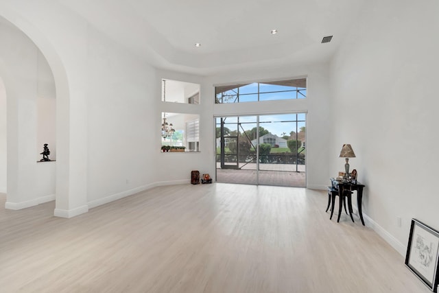 living room with arched walkways, recessed lighting, light wood-style flooring, and baseboards