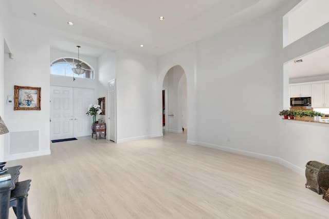 foyer entrance with arched walkways, light wood finished floors, recessed lighting, visible vents, and baseboards