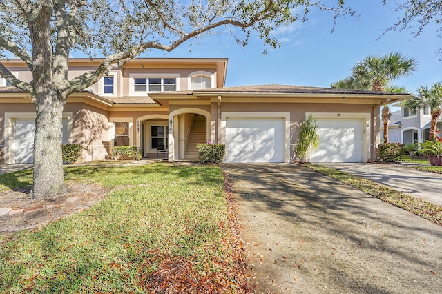 view of front of house featuring a front lawn, driveway, an attached garage, and stucco siding