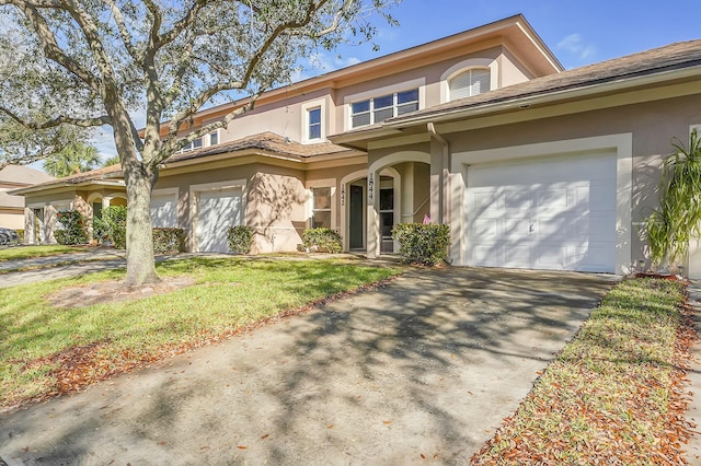 view of front of property featuring a garage, concrete driveway, a front yard, and stucco siding