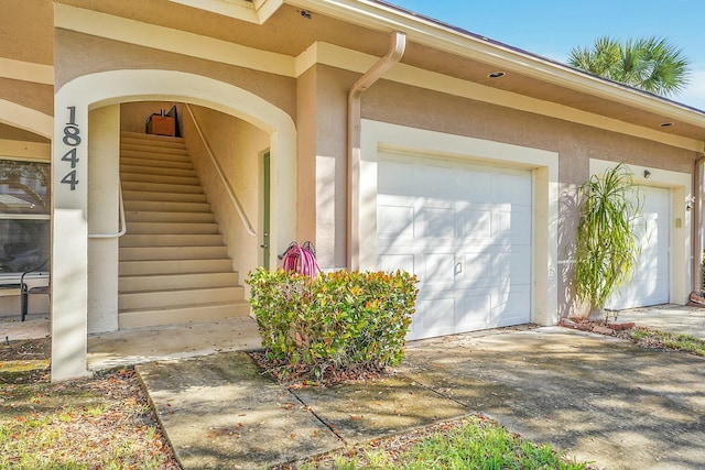 view of exterior entry with concrete driveway and stucco siding