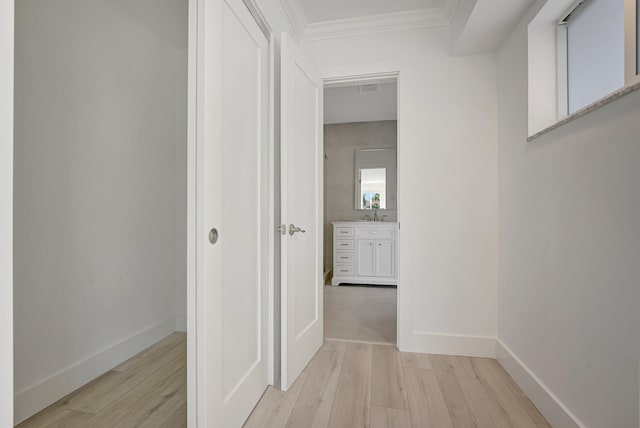 hallway featuring light wood-type flooring, baseboards, and crown molding