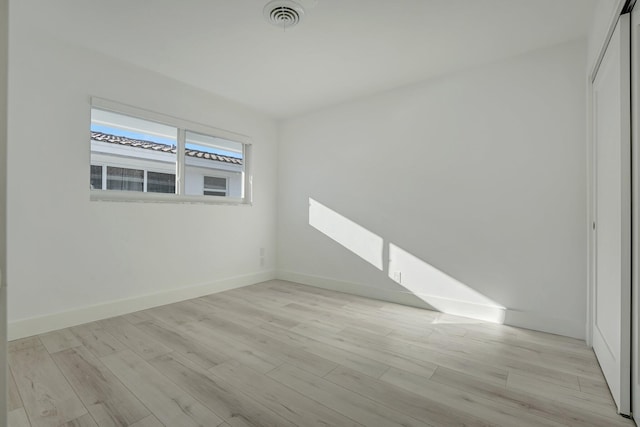 spare room with visible vents, light wood-style flooring, and baseboards