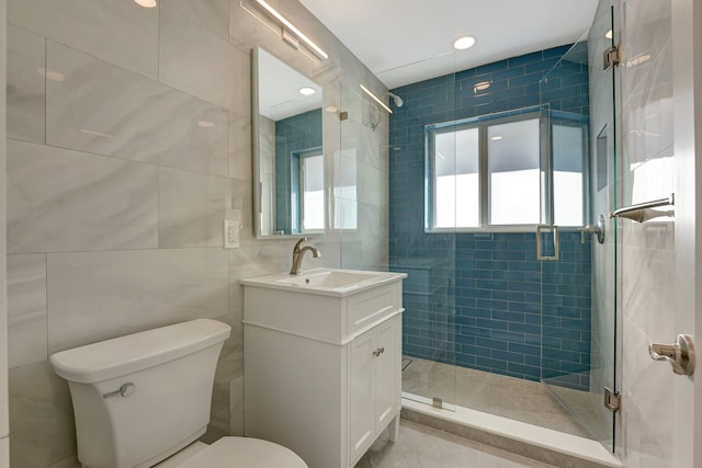 bathroom with toilet, a stall shower, tile walls, and vanity